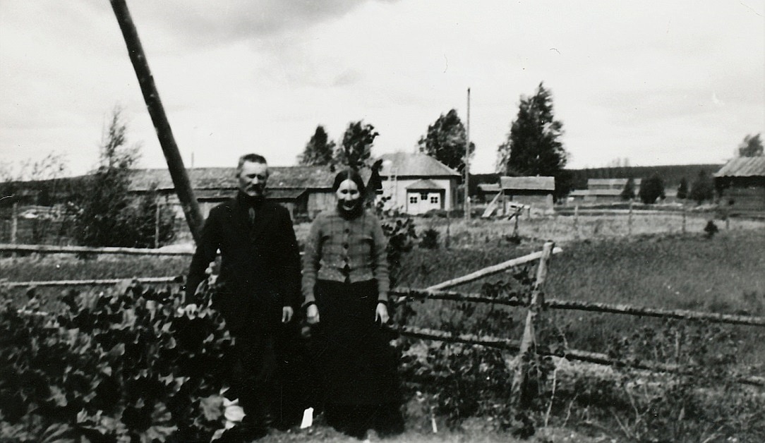 Josef Granholm och hans hustru Selma år 1928, alltså samma år som de byggde sitt hus i skogsbrynet. I bakgrunden syns Erik Anders Brobergs gård som revs någon gång i början på 2000-talet. 