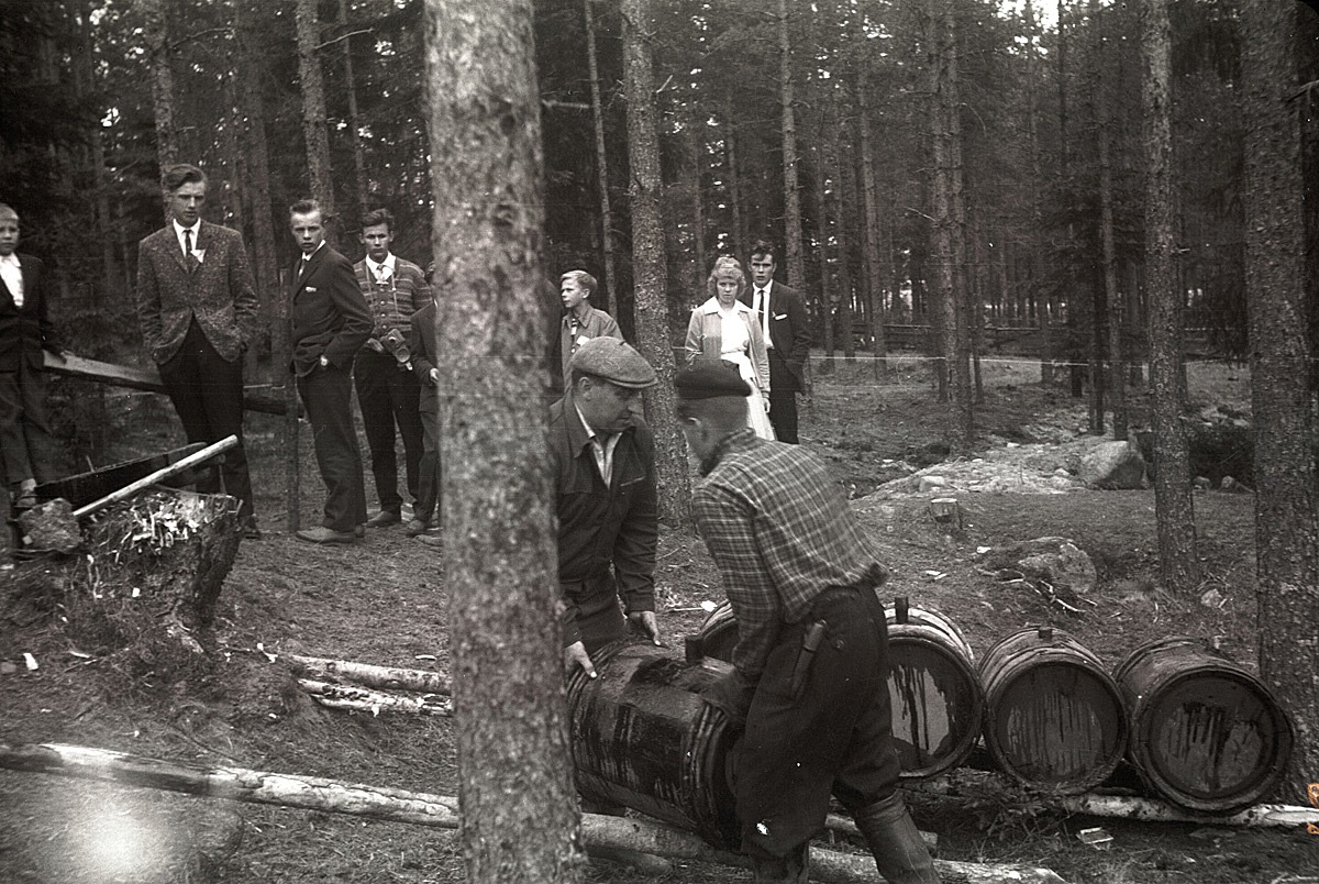 Sommaren 1961 visades i "Gamälstoråen", alltså i Vanhakylä hur det gick till då tjära tillverkades. Här lyfts ännu en tunna på plats, medan kostympojkar i bakgrunden står och ser på.