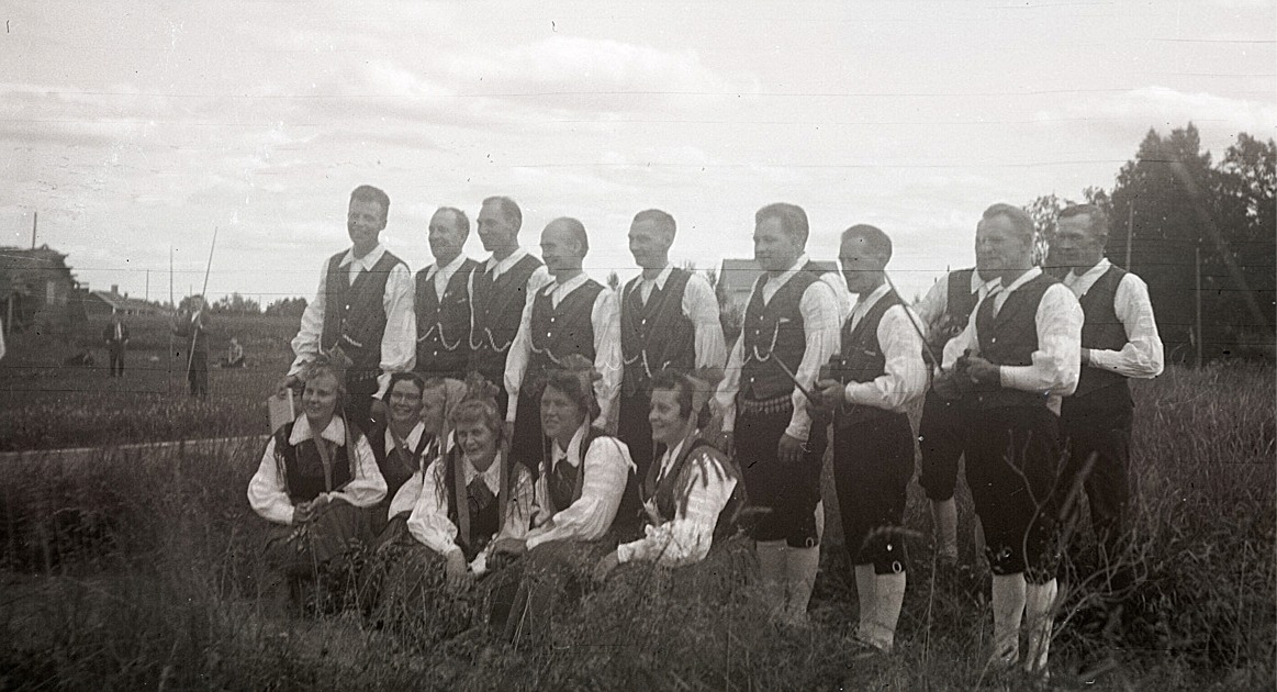 Sju par folkdansare och fyra spelmän på idrottsplan i Lappfjärd. Från vänster Venzel och Elin Smith, Lars och Gunvor Lillhannus, Nils och Ann-Lis Björklund, Eric och Irma Stens, Magnus och Gunnevi Åstrand, Ole (skymd) och Greta Åhlqvist och Helge och Maj-Britt Holm. Spelmännen är Torsten Pärus, Torsten Nyholm (skymd), Valter Enlund och Otto Fröberg.