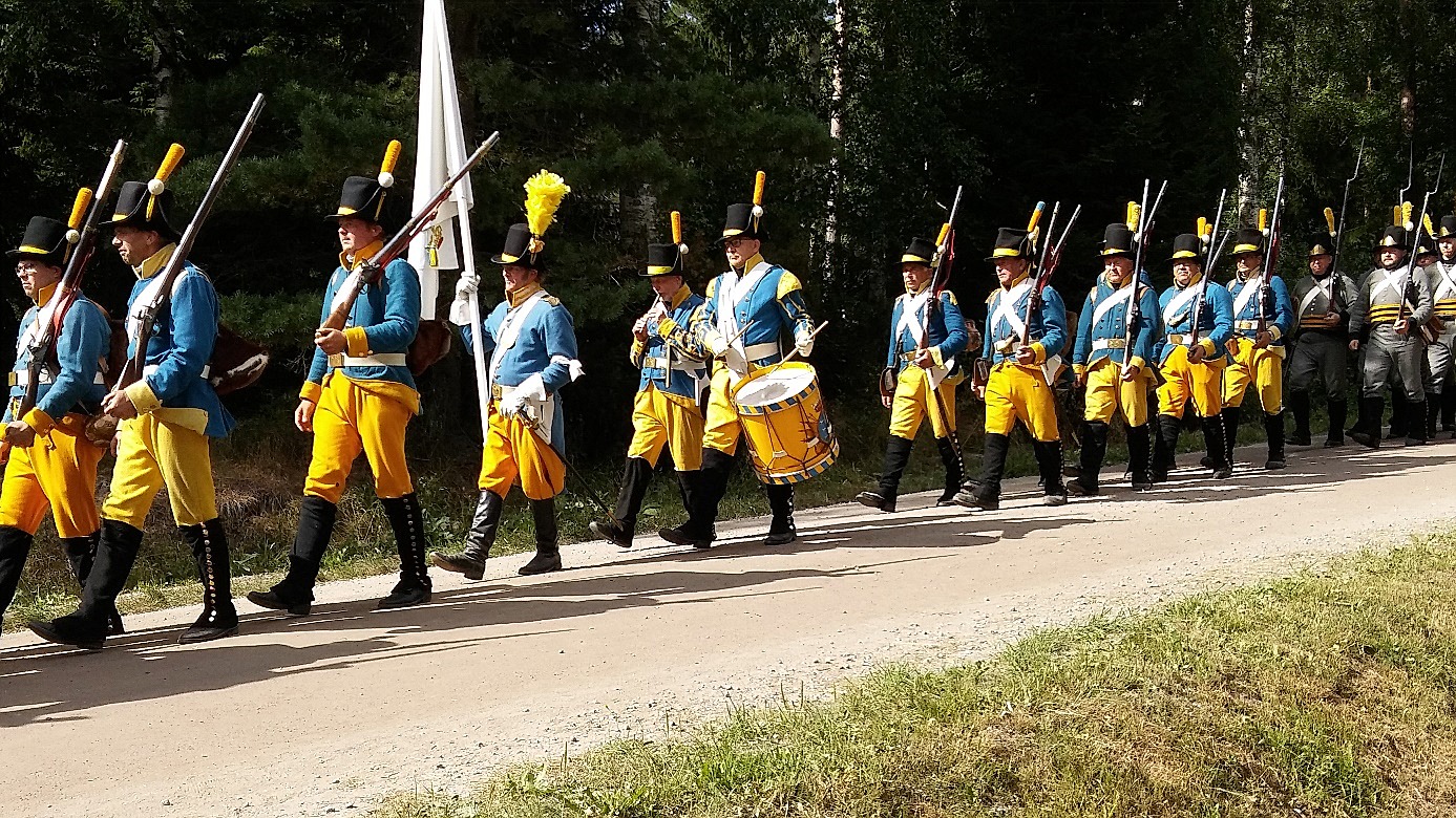 Mitt i bild en trumslagare i Oravais historiska förening år 2018. På 1700- talet skulle trumslagaren utrustas med 2 svarta halsdukar, 2 blåa klädesrockar, 2 gula västar, 2 gula ”böxor” och 2 hattar. 