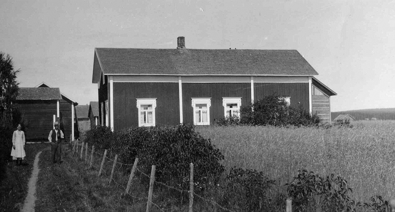 Den här gården flyttade Valentin Rosenback från Likvagnsjäälon mittemot folkskolan, upp till Åbackan under storskiftet 1900-1912. På bilden står Valentin tillsammans med dottern Elin Rosenback. Gården revs 1951 och stockarna användes på nytt då sonen Eskil Rosenback byggde den nya gården på andra sidan Åbackvägen.