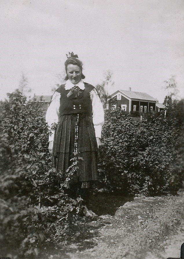 Ines Wiklund, senare Rosenback iklädd Lappfjärds folkdräkt. I bakgrunden syns Valentin Rosenbacks bondgård.